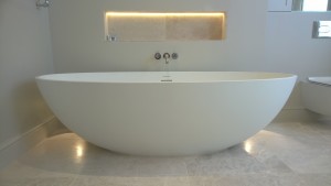 A free standing bath with recessed shelf and wall lighting