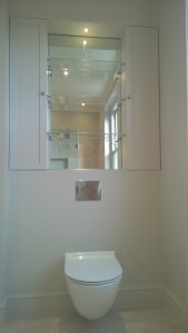 A wall hung WC with bespoke mirror cabinets and shelves above