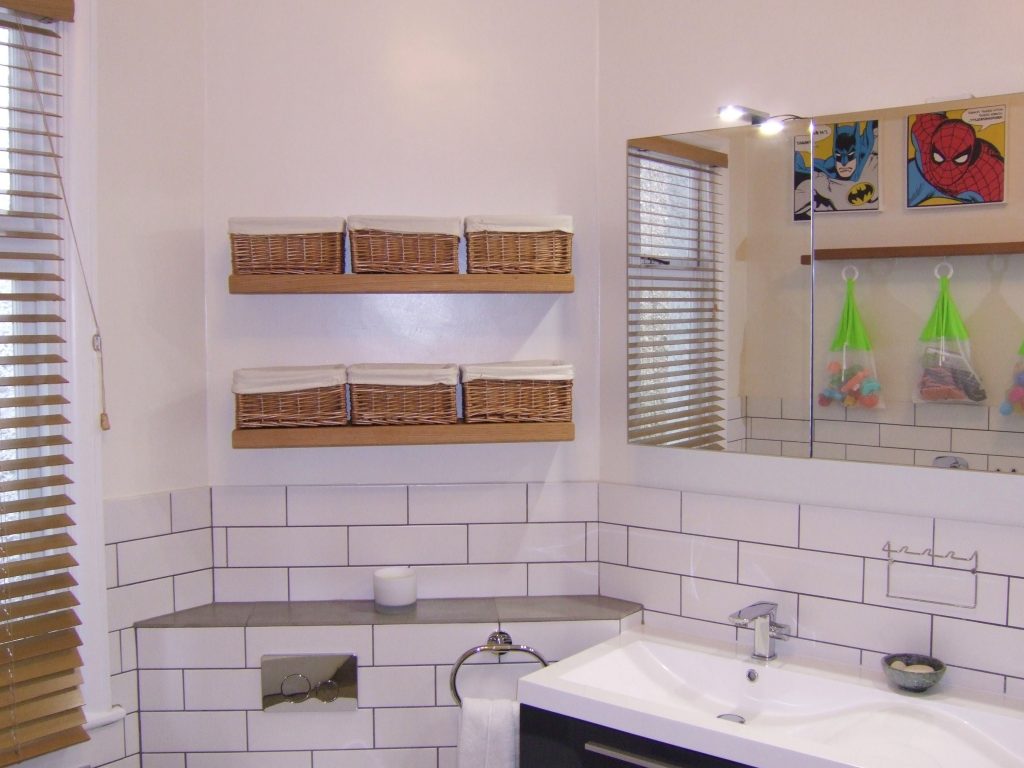 Bathroom picture with floating oak shelves and wicker baskets.
