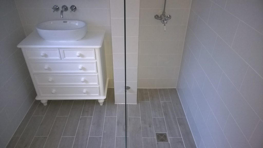 A wetroom shower with wood effect tiling and a vanity unit made from a reclaimed set of drawers
