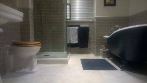 A bathroom with green metro wall tiles and matching dado rail